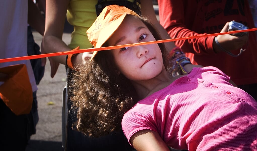 Een meisje danst de limbo tijdens een schoolactiviteit. Steeds minder kinderen spelen dagelijks buiten. (beeld anp / Robin Utrecht)