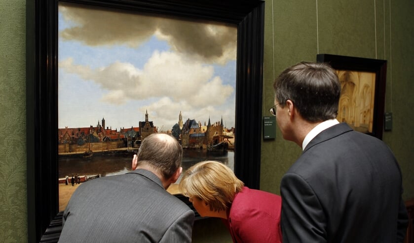 De Duitse bondskanselier Angela Merkel (rechts) bekijkt in 2010 het schilderij 'Gezicht op Delft' in het Haagse Mauritshuis. (beeld anp / Robert Vos)