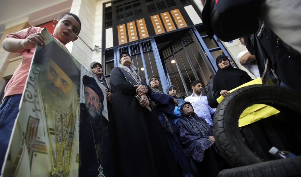 Mensen demonstreren in Beiroet (Libanon) voor de vrijlating van ontvoerde Syriërs en dragen daarbij foto's mee van de twee verdwenen bisschoppen. (beeld AFP PHOTO/JOSEPH EID
JOSEPH EID / AFP)