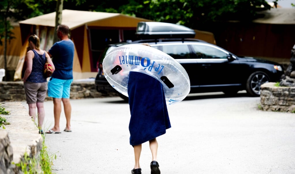 Een jonge campinggast verlaat het zwembad op camping Domaine Le Pommier in het Franse Villeneuve-de-Berg (Ardeche) met een zwemband op zijn schouders. (beeld anp / Robin Utrecht)