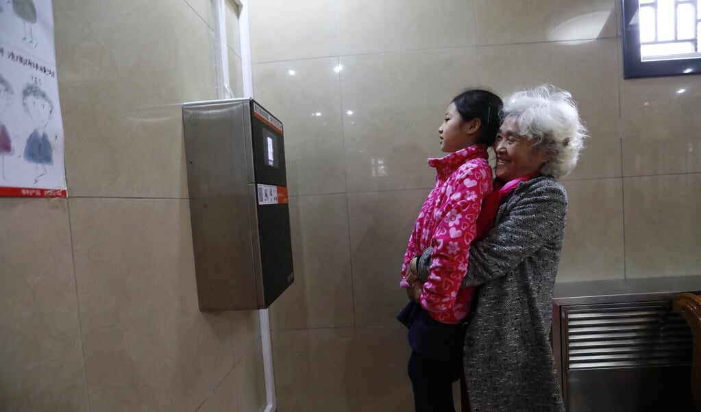 Een vrouw tilt haar kleindochter op om haar gezicht te laten scannen. In dit openbare toilet in Peking is gezichtsherkenning ingevoerd voor de verstrekking van toiletpapier, om de hoeveelheid per persoon tot 60 centimeter te kunnen beperken. Wil je méér, dan moet je 9 minuten wachten en kun je opnieuw 60 cm krijgen. (beeld epa / How Hwee Young)