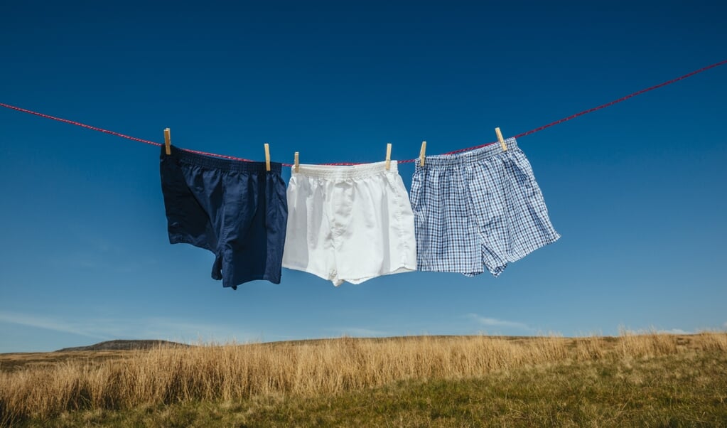 three pairs of boxer shorts hanging on a washing line on a rural hillside on a bright sunny clear sky day. (beeld iStock)