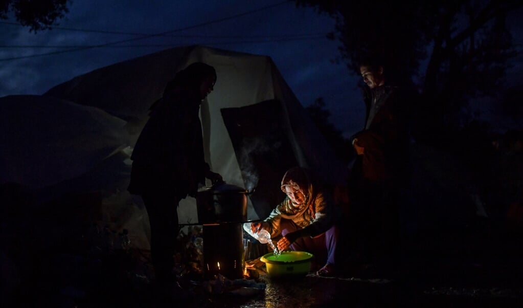 Een Afghaanse vluchteling kookt in de avondschemering bij haar tent op het Griekse eiland Lesbos. (beeld AFP / Aris Messinis)