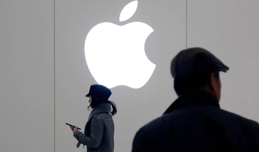 2019-01-04 12:59:14 epa07261010 A Chinese woman uses her mobile phone as she walks past an Apple logo outside an Apple Store in Beijing, China, 04 January 2019. Apple shares to plunge by 9.96 percent on 03 January 2019 after Apple CEO Tim Cook's commented ( beeld anp)