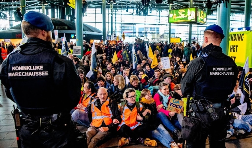 2019-12-14 12:20:47 SCHIPHOL - Actievoerders van Greenpeace protesteren in de hal van de luchthaven tegen de in hun ogen grote vervuiler Schiphol. ANP ROBIN UTRECHT ( beeld anp)