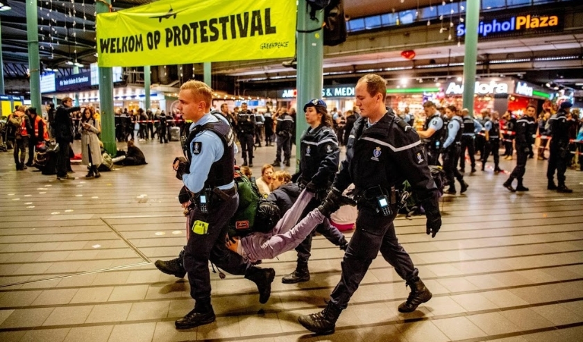 2019-12-14 17:41:07 SCHIPHOL - De Marechaussee verwijdert een actievoerder van Greenpeace uit Schiphol Plaza. Demonstranten protesteerden tegen de in hun ogen grote vervuiler Schiphol. ANP ROBIN UTRECHT ( beeld anp)