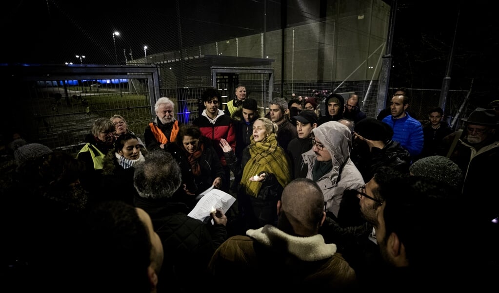 Deelnemers aan de wake, maandagavond, voor een Iraans gezin zingen bij Kamp Zeist in het Farsi een lied. (beeld Jeroen Jumelet)