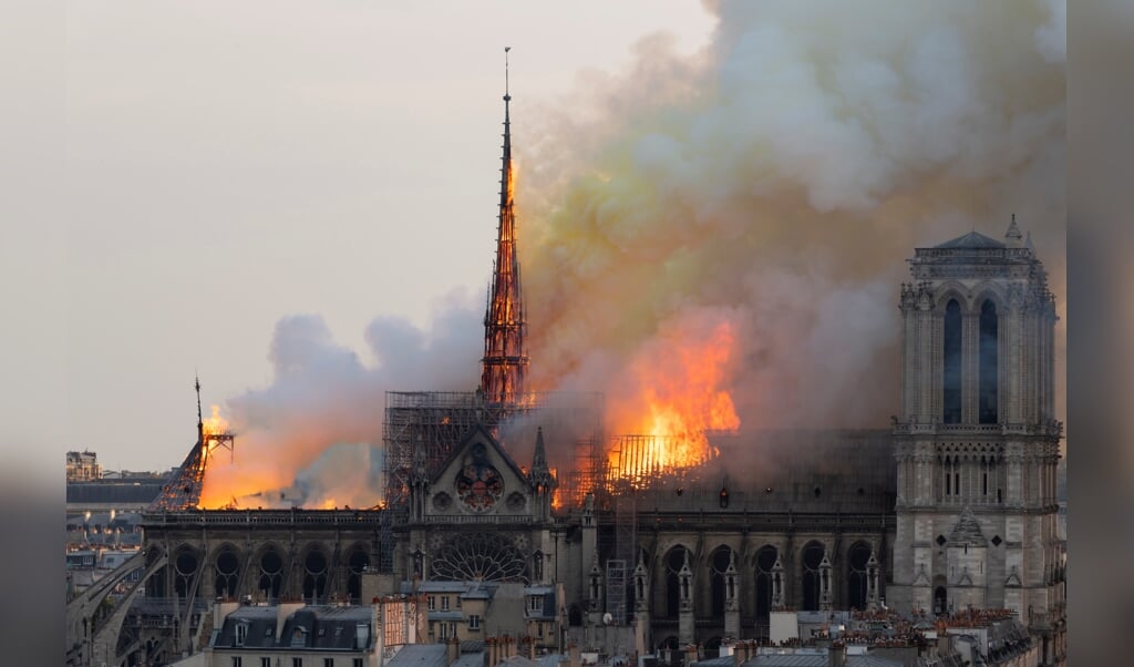 De brandende Notre-Dame in Parijs, op 15 april 2019, met de brandende centrale torenspits die daarna zou instorten. (beeld Fabien Barrau / afp)