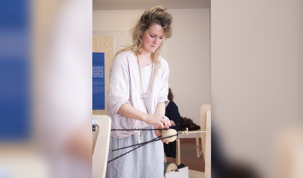 Sanne Visser knoopt het garen van mensenhaar in haar zelf gebouwde touwmachine. (beeld studio Sanne Visser)