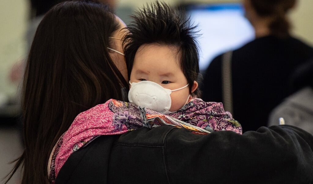 Een vrouw in Hongkong heeft haar kind een mondkapje voorgedaan, in januari dit jaar. Tegen het coronavirus werden meteen strenge maatregelen genomen, vanwege het collectieve SARS-trauma, maar ook vanuit gemeenschapszin. (beeld afp / Philip Fong)