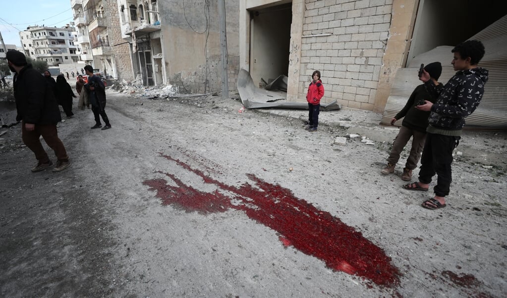 Syrische kinderen kijken naar een plas bloed na een luchtaanval op Ariha, een stad in de provincie Idlib, die tenminste negen burgers het leven kostte. ( beeld anp)
