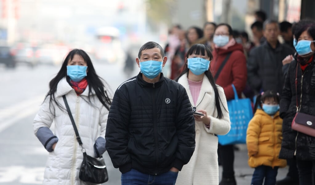 Chinese inwoners dragen maskers in de buurt van de vismarkt in Wuhan, waar veel besmettingen met het coronavirus zijn gemeld. (beeld epa)