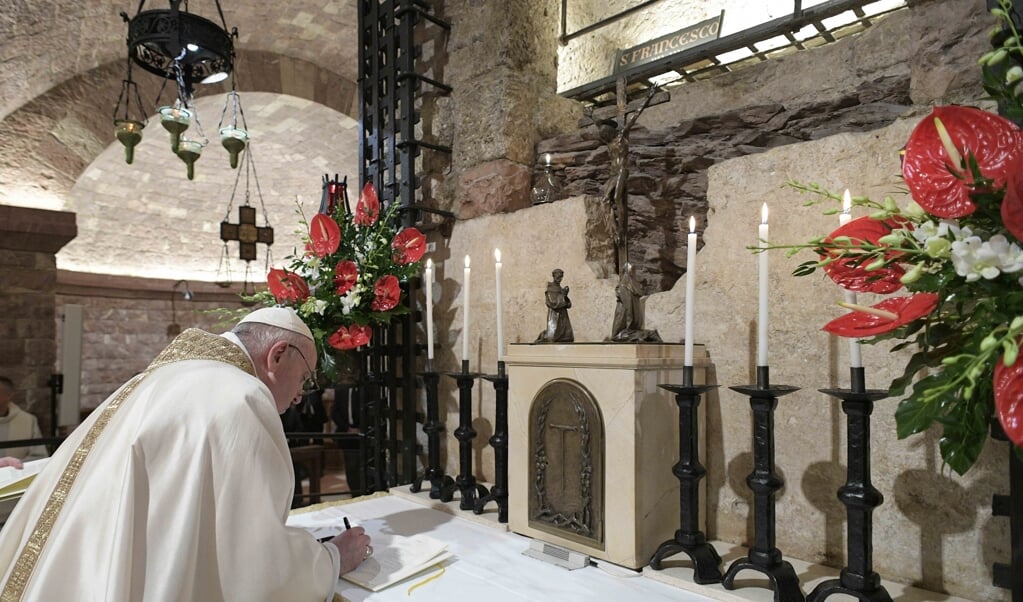<p>Paus Franciscus ondertekent bij het graf van Franciscus van Assisi zijn nieuwe encycliek 'Fratelli Tutti'. VATICAN MEDIA / AFP</p> (beeld Handout / Vatican Media / afp)