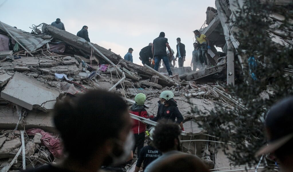 <p>Vrijwilligers zoeken naar overlevenden onder het puin in de Turkse stad Izmir.</p> (beeld afp / Mert Cakir)