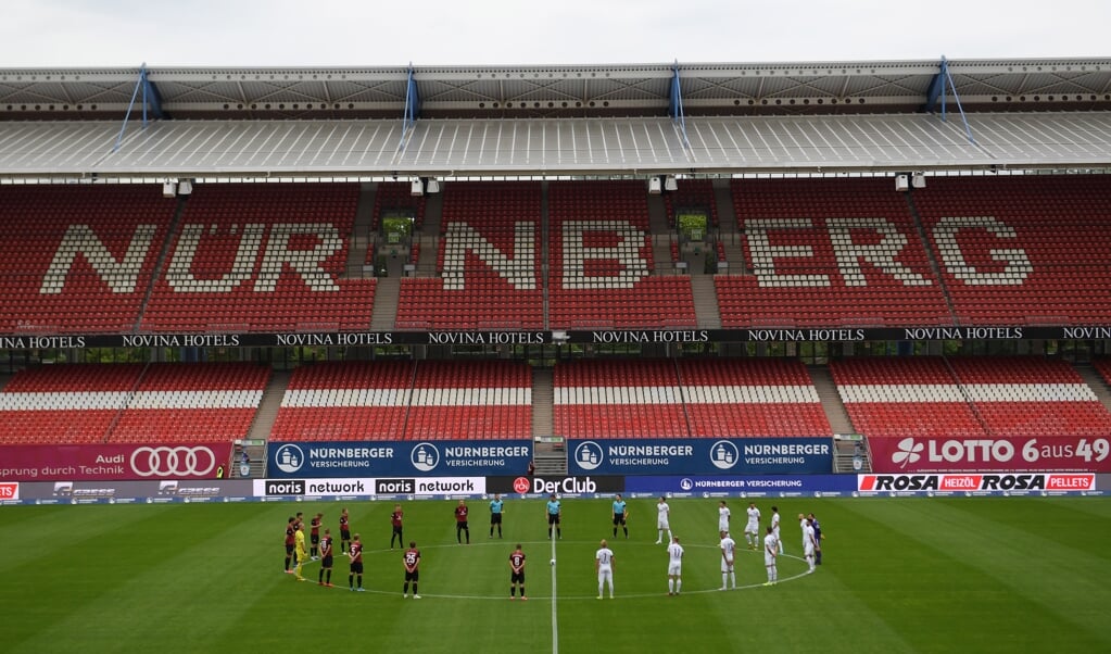 Spelers houden in het stadion van FC Nürnberg een minuut stilte voor de slachtoffers van corona. (beeld epa / Matthias Hangst)
