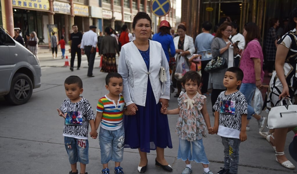 <p>Archieffoto uit juni 2019 van een Oeigoerse met kinderen op straat in Kashgar in de Chinese provincie Xinjiang.</p> (beeld afp / Greg Baker)