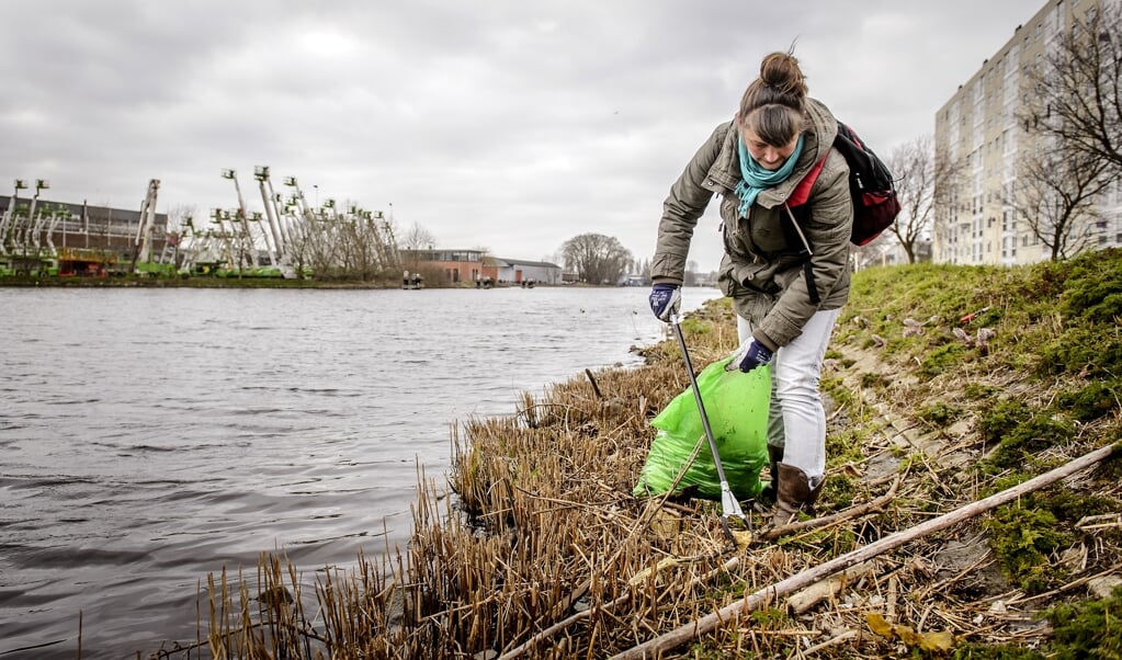 <p>Deelnemers aan de schoonmaakactie Schone Schie maken de oevers langs de Rotterdamse Schie schoon.</p> (beeld anp / Remko de Waal)