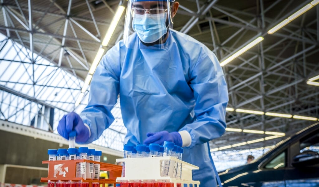 <p>Een medewerker van de GGD Amsterdam neemt een coronatest af in een testlocatie bij de RAI.</p> (beeld anp / Lex van Lieshout)