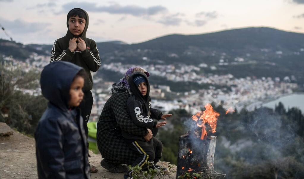 <p>Een man steekt een vuur aan voor zijn gezin in het onofficiële kamp van het eiland Samos</p> (beeld afp / Aris Messinis)