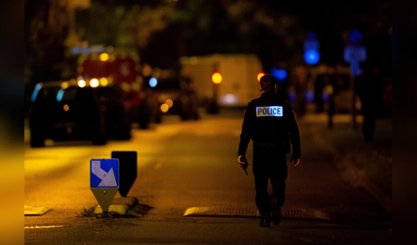 <p>Een Franse agent patrouilleert in de Parijse wijk waar vrijdagavond een leraar vermoord werd.</p> (beeld afp / Abdulmonam Eassa)