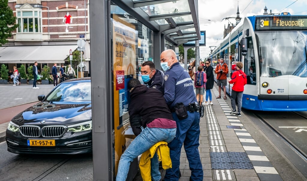 <p>Handhavers in actie in Amsterdam. 'Als jongeren minder perspectief zien, kan het zijn dat ze zeggen: “Ik heb schijt aan corona”.'</p> (beeld Joris van Gennip)