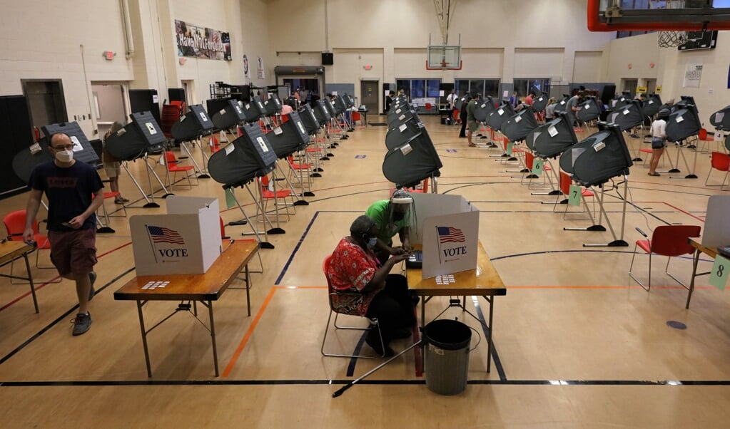 <p>Een vrijwilliger helpt een kiezer in een stembureau in Texas. Op verschillende plekken in het land kunnen burgers al stemmen.</p> (beeld epa / Aaron Sprecher)