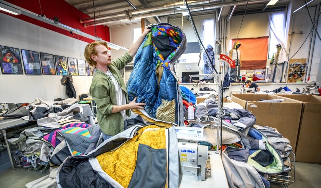 Bas Timmer met tweedehandsslaapzakken waarvan in zijn atelier sheltersuits voor daklozen worden gemaakt. (beeld Raymond Rutting )