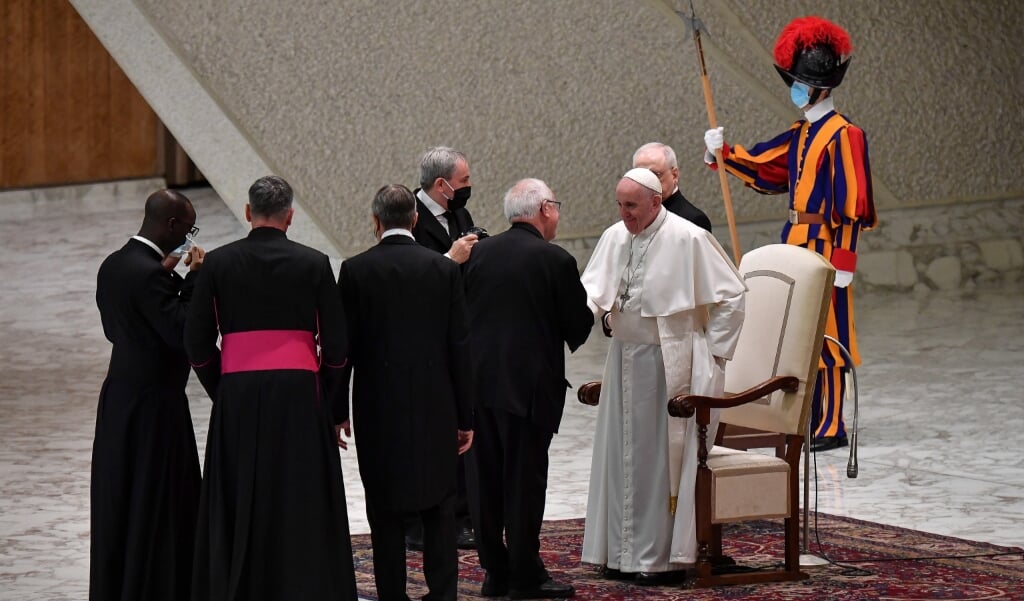 Terwijl deelnemers in de grote aula hun maskers verplicht dragen volgens de Vaticaanse regels, draagt paus Franciscus het masker niet. Na afloop van de algemene audiëntie op woensdag groette hij verschillende mensen die hij ongemaskerd toesprak. De beide geestelijken links op de foto doen hun masker af alvorens de paus de hand te geven. (beeld Epa/alessandro di meo)