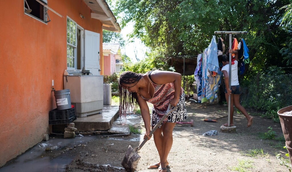 Jenny Vrutaal uit Willemstad graaft een geultje voor het spoelwater van haar verouderde wasmachine, die geen afvoer heeft. (beeld Sabine van Wechem)