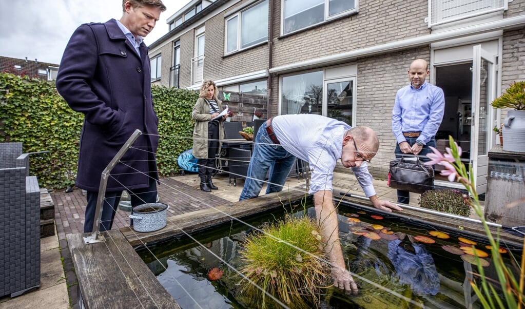 De wijkrechter Jerzy Luiten (links) kijkt samen met de klagende buurman (rechts) en de bewoner naar de vijverpomp. Achter in beeld de griffier. (beeld Raymond Rutting)