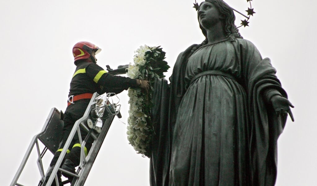 Het Mariabeeld op het Piazza di Spagna krijgt een bloemenkrans, voor de jaarlijkse viering van het dogmafeest op 8 december. Maar die ging dit jaar niet door. (beeld afp / Andreas Solaro)