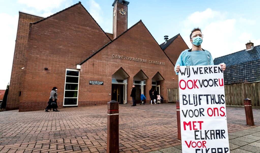 Een zorgmedewerker voert op eerste kerstdag actie tegen fysieke kerkdiensten, bijvoorbeeld in de Rehobothkerk in Barneveld. (beeld anp / Remko de Waal)
