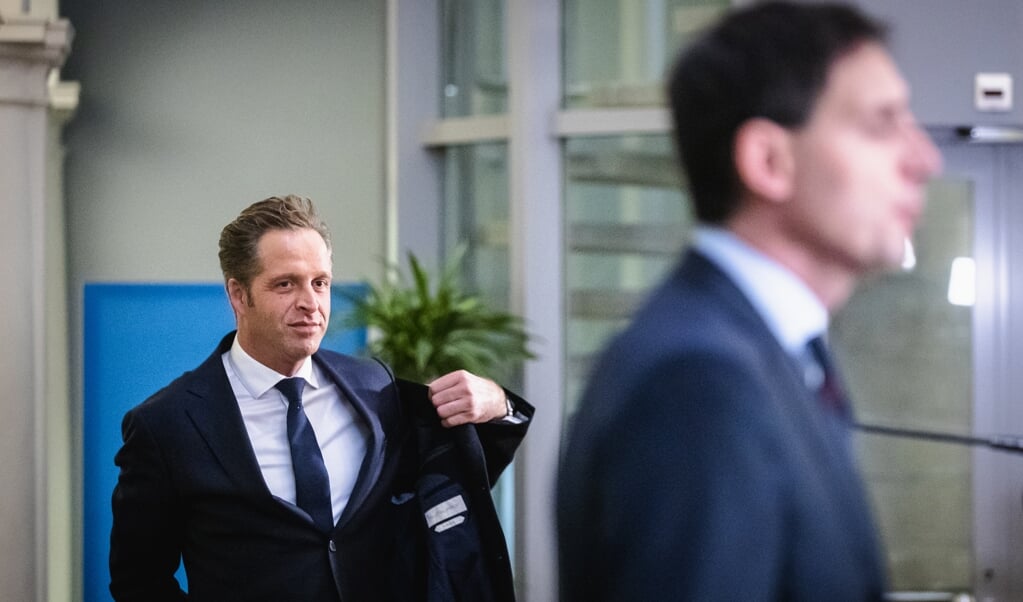 Hugo de Jonge trekt zijn jas aan nadat hij samen met Wopke Hoekstra de pers te woord heeft gestaan. (beeld anp / Sem van der Wal)