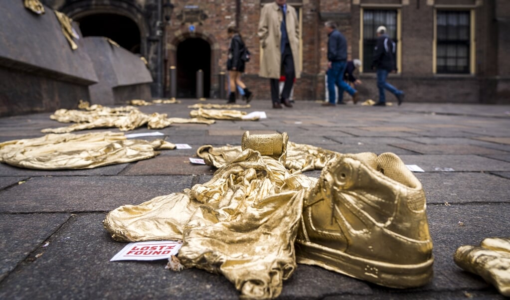 Een kunstzinnige actie voor mensenrechten, mei 2019, Den Haag: gouden kinderkleren vestigen de aandacht op meer dan tienduizend verdwenen vluchtelingenkinderen in Europa. Mensenrechten zijn nauw verbonden met wie God is. (beeld anp / Lex van Lieshout)