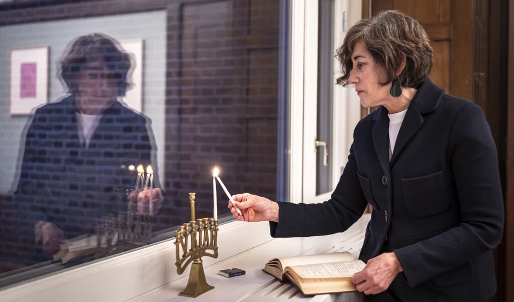 Judith Frishman steekt donderdagavond het eerste van de in totaal 44 kaarsjes voor de Chanoeka-week aan. (beeld Martin Waalboer)