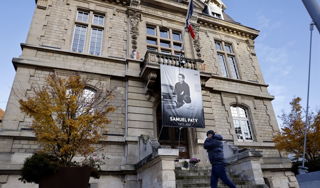 Bij het stadhuis van Conflans-Sainte-Honorine hangt als eerbetoon de beeltenis van Samuel Paty. (beeld afp / Thomas Coex)