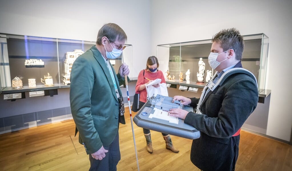 Hannes Wallrafen legt in het Rijksmuseum de werking van zijn prototype kaart uit aan een vrijwilliger. (beeld Jeroen Jumelet)