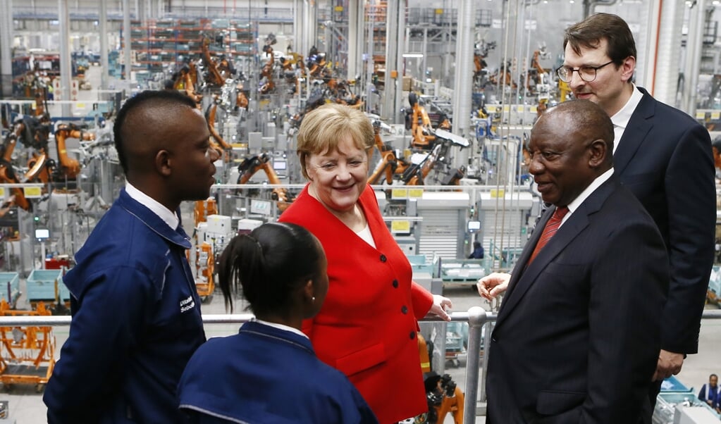 De Duitse bondskanselier Angela Merkel op bezoek in Zuid-Afrika, in februari van dit jaar. Hier ontmoet ze stagiaires in de BMW-fabriek bij Pretoria. Rechts president Cyril Ramaphosa. (beeld afp / Phil Magakoe)