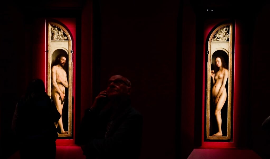 Bezoekers van de tentoonstelling Van Eyck kijken naar de panelen Adam en Eva. Hamvraag: zijn de vijgenblaadjes origineel, of preutse toevoegingen? (beeld epa / Stephanie Lecocq)