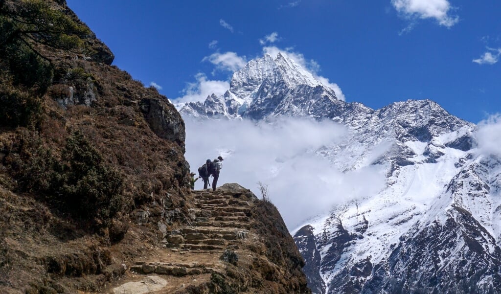 Wandelaars op een vrijwel verlaten pad nabij Kathmandu, met op de achtergrond de Mount Everest. Na de lockdown werd de lucht in India zo schoon dat het bergmassief vanuit Bihar zichtbaar was. (beeld afp / Prakash Mathema)