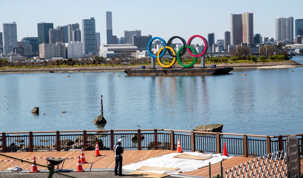 Werkzaamheden nabij de Olympische ringen in Tokio, een dag na de historische beslissing de Spelen met een jaar uit te stellen. (beeld afp / Behrouz Mehri)