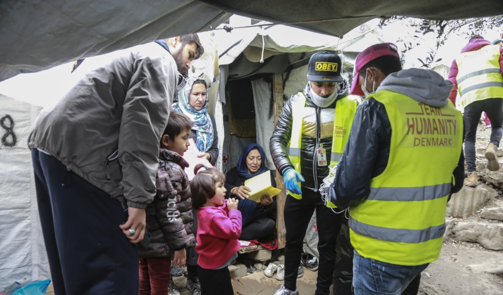 Hulpverleners delen handgemaakte mondkapjes uit in kamp Moria op het Griekse eiland Lesbos. (beeld anp / Manolis Lagoutaris)