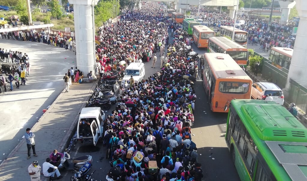 Duizenden arbeidsmigranten verdrongen zich zaterdag in Delhi, in de hoop toch een bus de stad uit te kunnen nemen. (beeld Bhuvan Bagga / AFP)