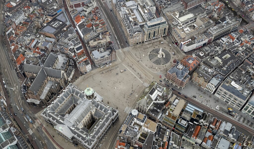 Luchtfoto van een vrijwel lege Dam in Amsterdam. Nu volgen mensen de regels goed op, maar als de coronacrisis lang gaat duren, kan er onrust ontstaan. (beeld anp / Robin van Lonkhuijsen)