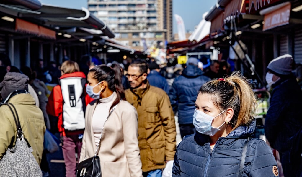 Bezoekers aan de Haagse markt lopen met mondkapjes op. Ondanks de coronaregels is het er erg druk. (beeld anp / Robin Utrecht)