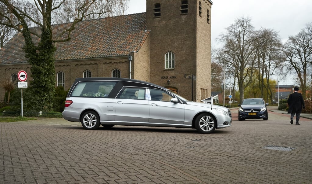 Een rouwauto rijdt weg bij de Ichthuskerk in Hasselt, een van de kerken waar lichamen zijn opgebaard van mensen die aan het coronavirus zijn overleden. (beeld Dick Vos)