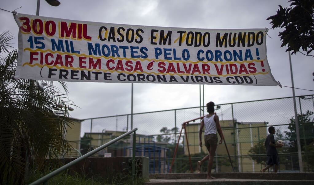 ‘300.000 gevallen wereldwijd, 15.000 doden door corona! Blijf thuis, red levens’, staat op een spandoek in Rio de Janeiro. (beeld afp)