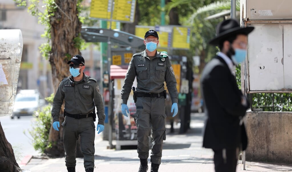 Tijdens hun patrouille door de lege straten van Bnei Brak dragen agenten van de Israëlische grenspolitie mondkapjes om zich te beschermen tegen het coronavirus. (beeld epa / Abir Sultan)