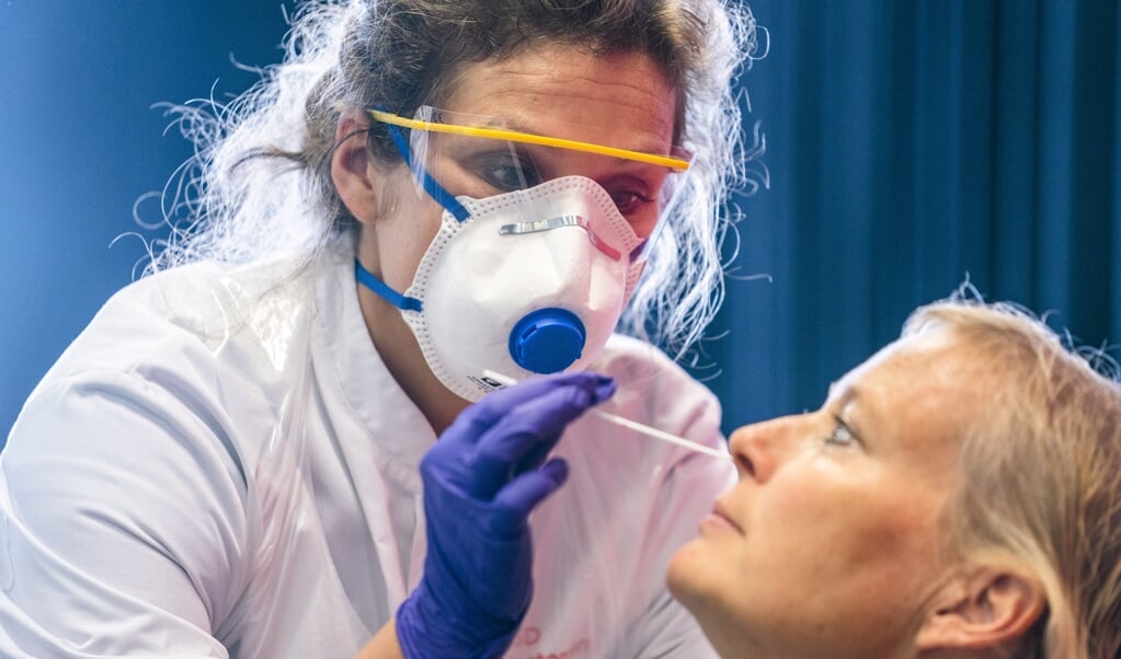 Een zorgmedewerker wordt getest op het coronavirus door medewerkers van de GGD Amsterdam. (beeld anp / Jeroen Jumelet)