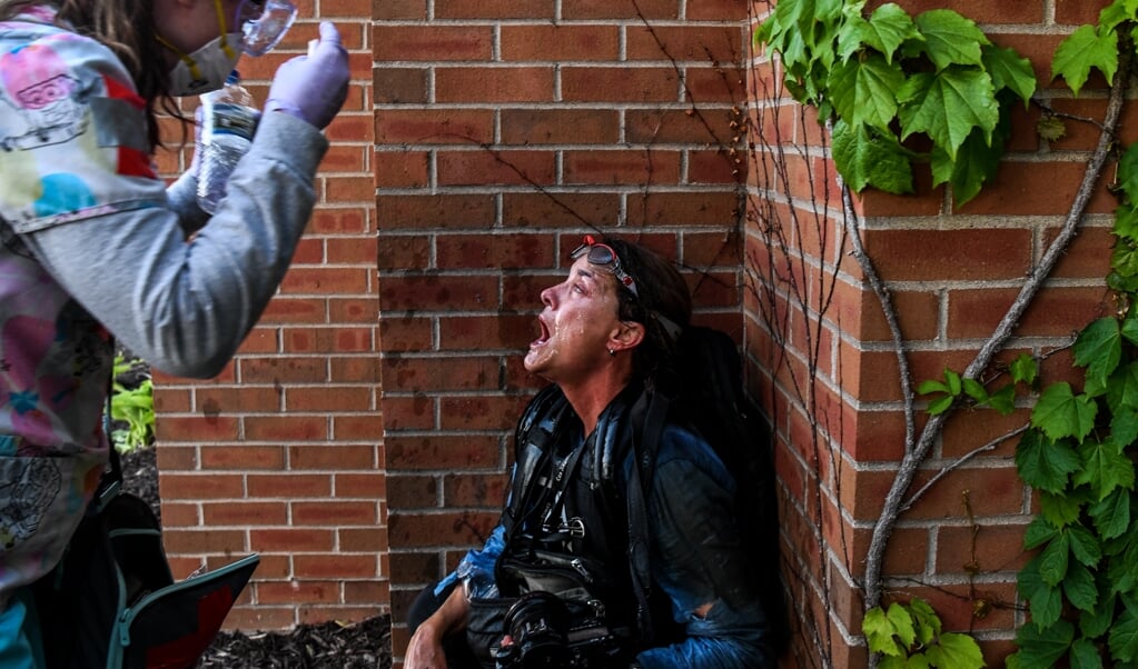 Tijdens een antiracismedemonstratie in Minneapolis wordt een gewonde journalist geholpen door een demonstrant. (beeld afp / Chandan Khanna)